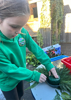 A child from year 1 and 2 creating wreaths for the christmas fair